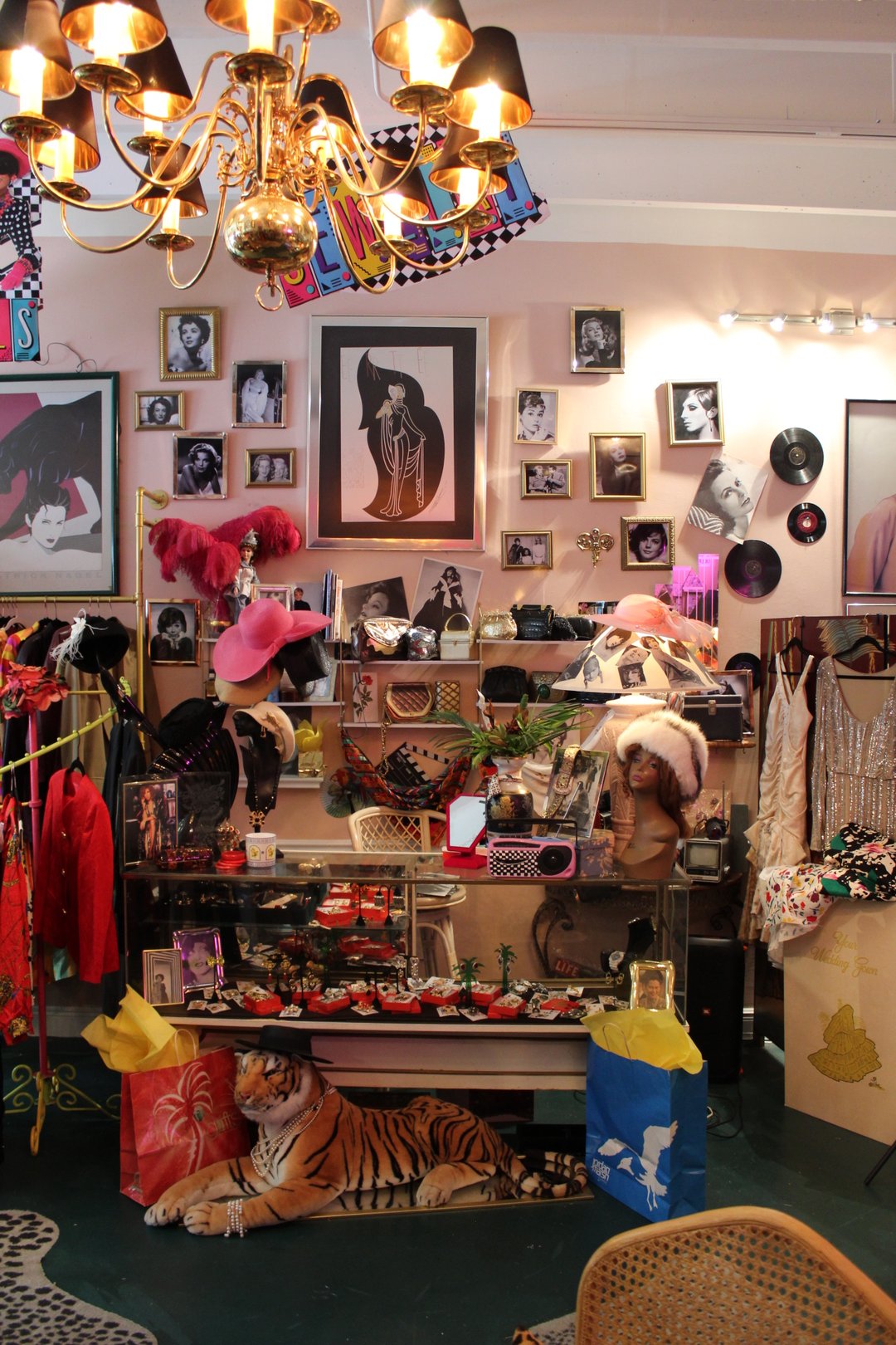Inside Turn Back The Clock Shop in Miami: pink walls with vintage glamour photos, hats, jewelry cases, and a chandelier