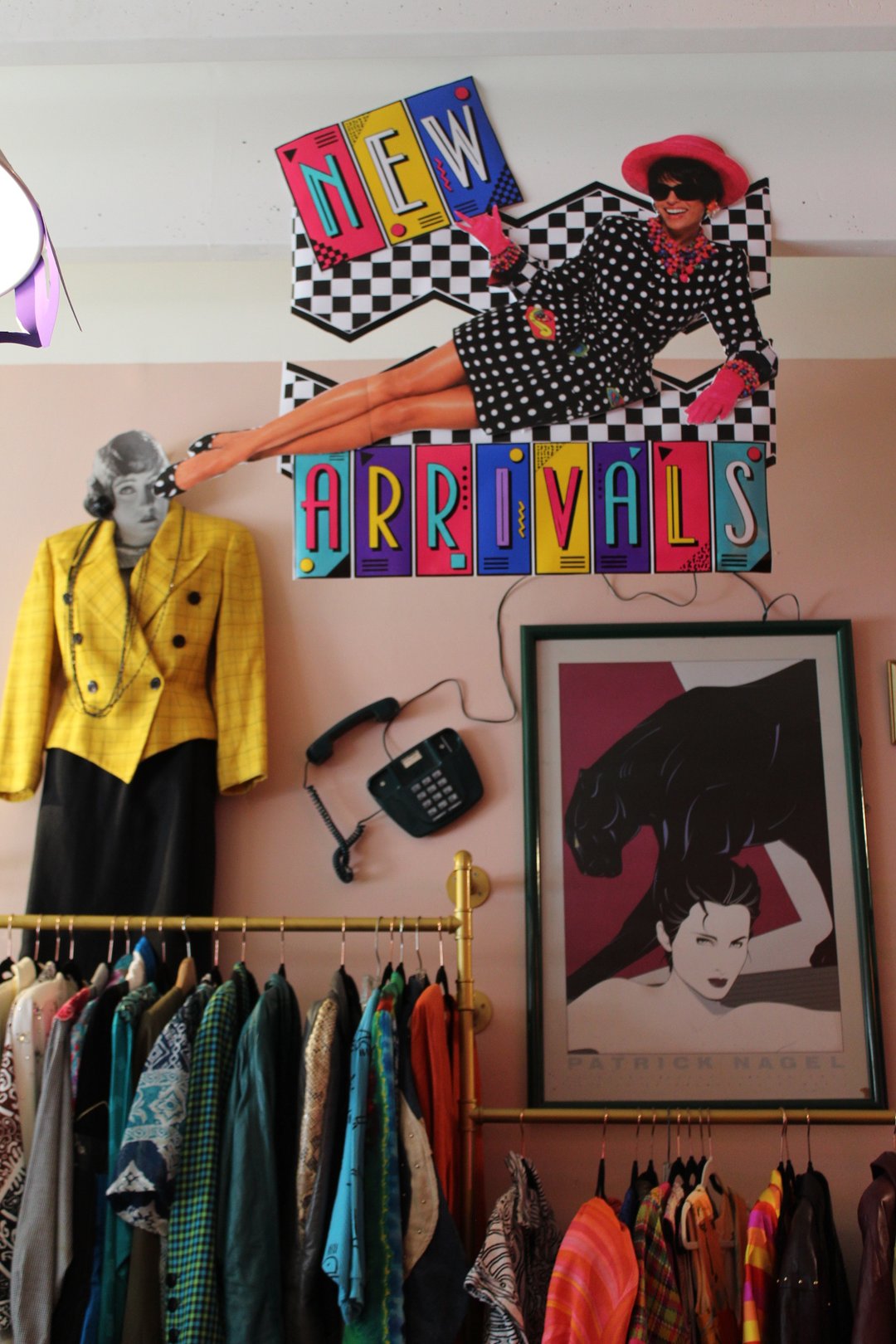 New arrivals corner at Turn Back The Clock Shop with a retro checkerboard sign, Patrick Nagel print, and vintage clothing racks
