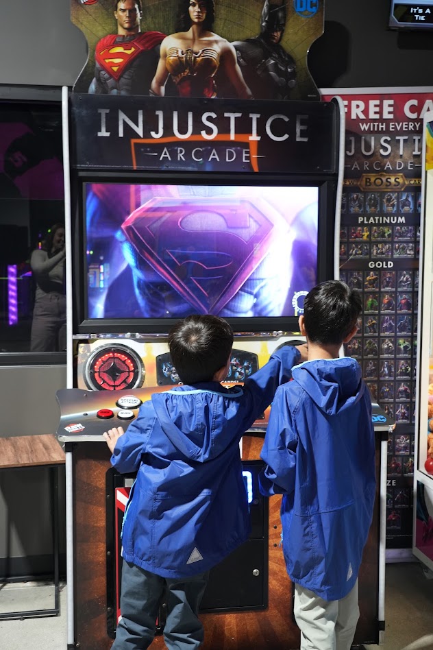 Two boys playing the Injustice Arcade game