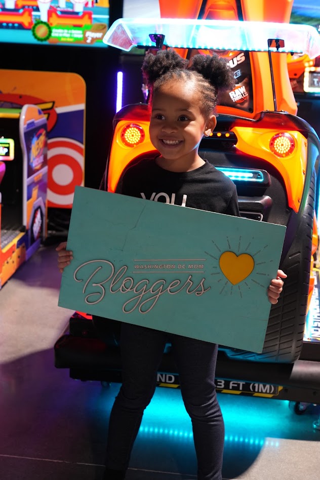 A little girl holding the Washington DC Mom Bloggers sign