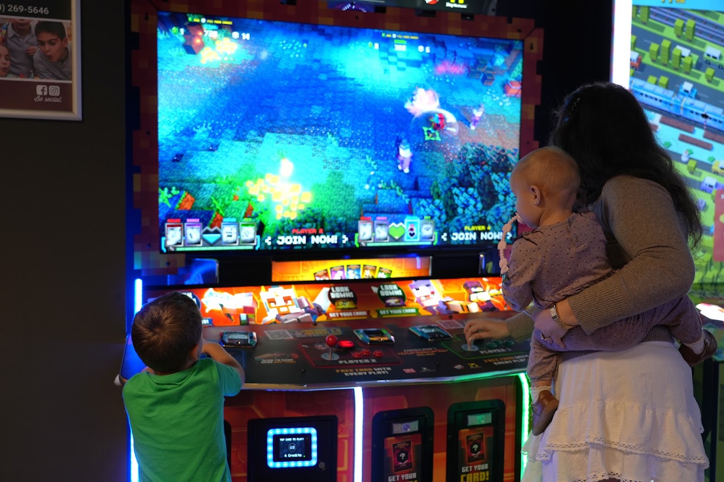 A mom, baby and son playing the Minecraft arcade game