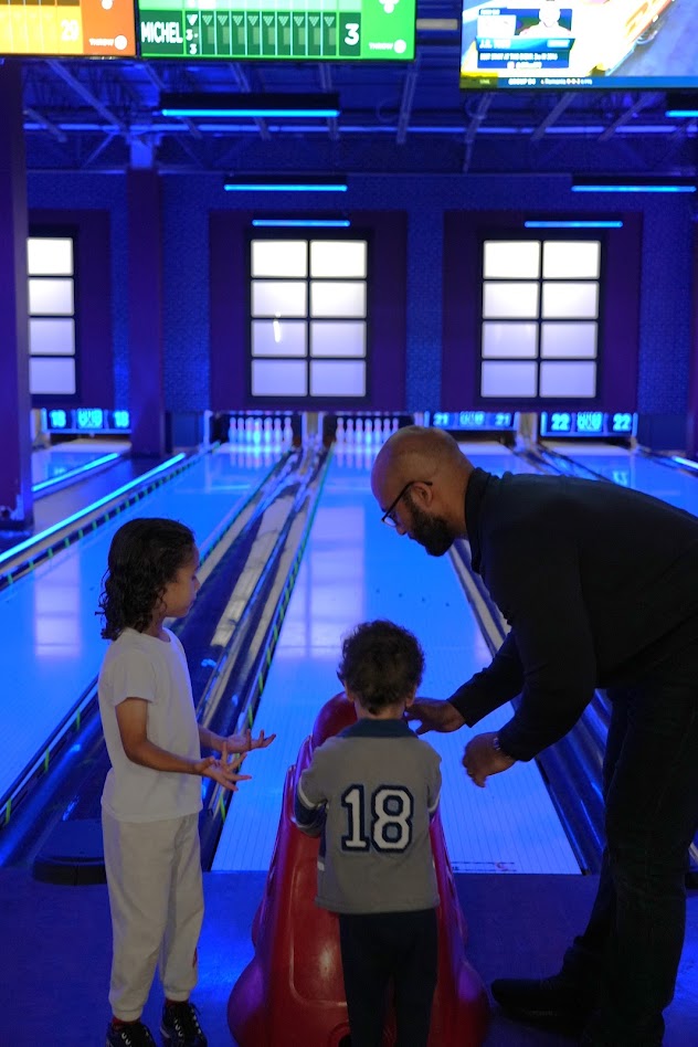 A dad helping his kids bowl with a bowling ramp